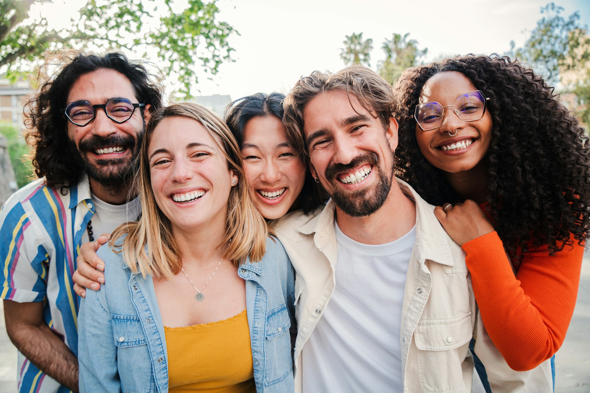 Portrait of a group of friends laughing together and looking at camera. Five young multiracial